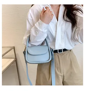 Detail of light blue crossbody bag with gold hardware and wide shoulder strap