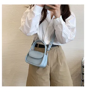 Detailed close-up of sky blue leather square bag with adjustable shoulder strap