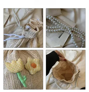 Détail du sac seau en paille avec chaîne en perles et écusson floral à carreaux