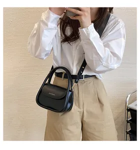 Detail of a black leather mini square bag with golden text print and curved handle