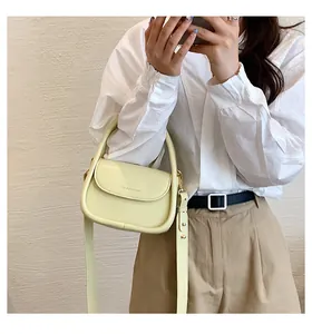 Close-up of a pale yellow textured leather crossbody bag with light gold hardware details