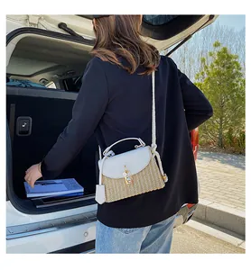 Detail van geweven stro en wit lederen crossbodytas met gouden metalen gespsluiting