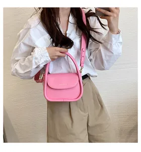 Pink matte leather crossbody bag featuring a cylindrical handle and wide shoulder strap