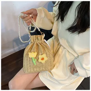 Détail du sac seau en paille tissé main avec accents floraux et grande anse en perles