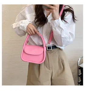 Detailed view of a pink minimalist crossbody bag with textured leather and sturdy handle