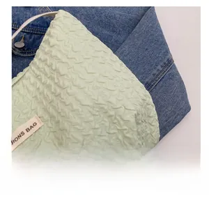 Detail view of light green pleated bubble fabric bag with a white leather handle