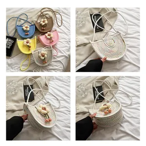 Detail of woven crescent crossbody bag with 3D crochet floral charm and slim strap