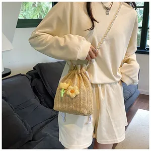 Vue détaillée du sac seau en paille tressée avec fleurs et bandoulière en perles