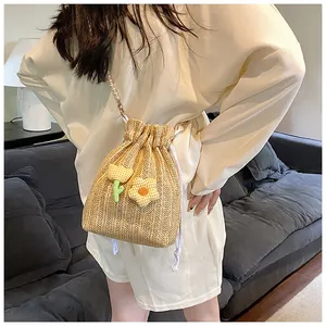 Détail du sac seau en paille tressée avec chaîne en perles et décorations florales