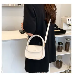 Close-up of off-white PU leather crossbody bag featuring a wide handle and flap closure