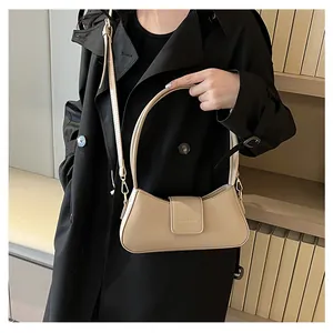 Französische beige Unterarmtasche aus Leder mit Metallverschluss an schwarzem Mantel