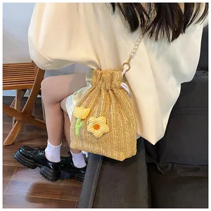 Détail du sac seau en paille tissée avec chaîne en perles et broderies florales