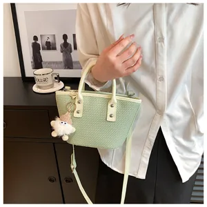 Detail of mint green bucket bag with cross-grain texture and cute plush charm pendant