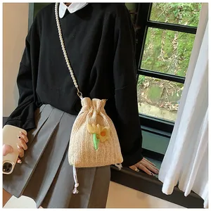 Détail du sac seau en paille tressée avec bandoulière en perles et décor de fleurs