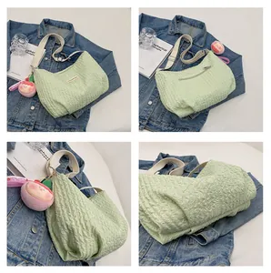 Detail of light green bubble textured crossbody bag with adjustable wide strap and peach charm
