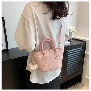 Detailed texture of pink woven tote bag with adjustable shoulder strap and cute plush charm
