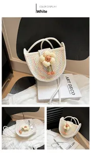 Detail of woven straw bag for girls with beige flower decoration and white rope straps