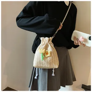 Détail du sac seau tissé beige avec broderie tulipe 3D et bandoulière en perles