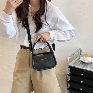 Minimalist black leather crossbody bag with top handle and golden logo for women fashion