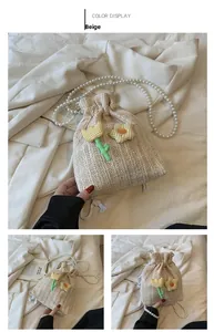 Détail d'un sac seau beige tissé avec bandoulière perles et breloques tulipes