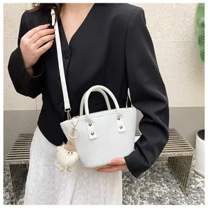 White woven tote bag detail featuring a cute plush lamb pendant and dual handles
