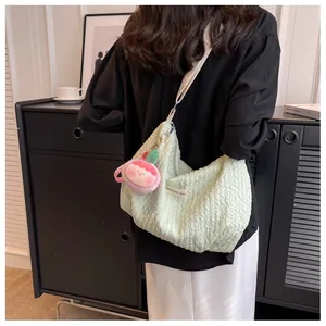 Detail of mint green ruched cloud bag with wide canvas strap and strawberry plush charm