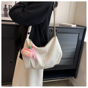 Detail of white pleated cloud bag texture with fashion label and pink plush charm