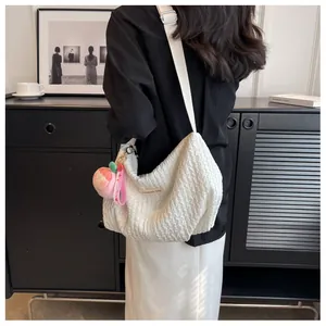 Detail view of white ruched cloud bag with peach plush charm and adjustable strap