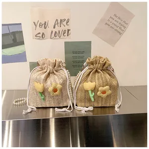 Détail de sacs seaux en paille tressée avec fleurs et poignées en perles élégantes