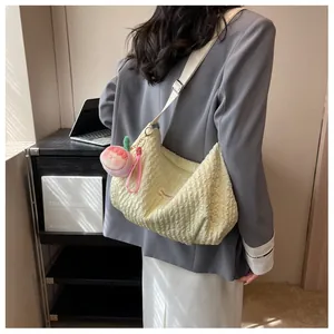 Detail of light yellow pleated cloud bag with pink peach charm and adjustable strap