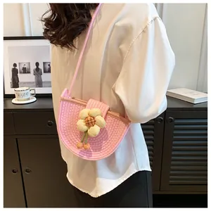 Detail of pink woven crossbody bag featuring a large yellow flower and bead tassel