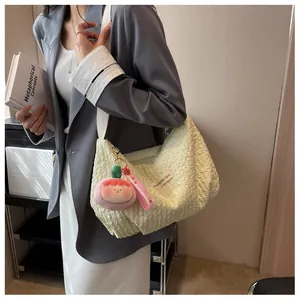 Detail of light yellow ruched cloud bag with pink plush pendant and white strap