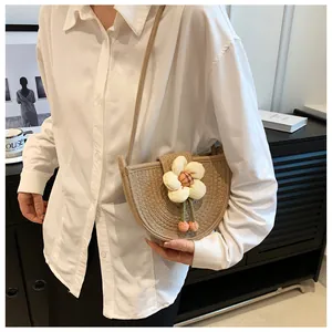 Detail view of woven semicircular crossbody bag featuring a 3D floral accent for women
