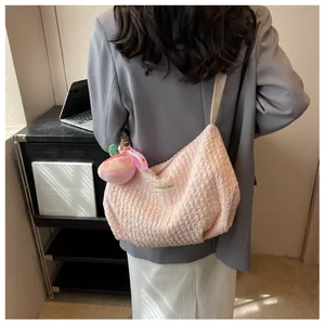Macro detail of pink bubble pleat cloud bag with a peach plush charm and wide strap