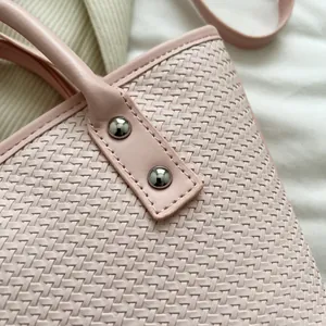 Elegant pink woven leather tote bag with silver rivets and textured handle detail