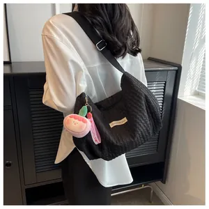 Detail shot of black ruched cloud bag with pink doll charm and branded fashion label