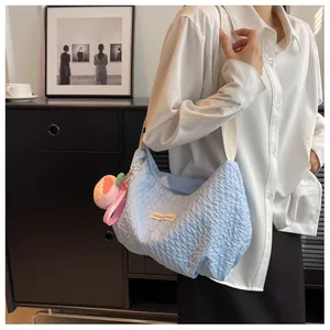 Detail of light blue ruched cloud bag featuring bubble texture and peach plush charm