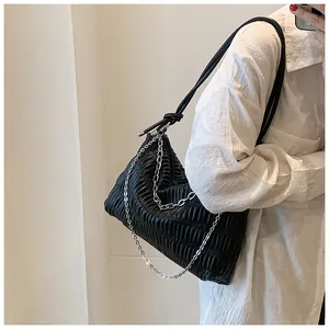 Detail of ruched black leather tote featuring silver chain accents and knotted strap design