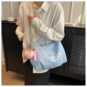 Detail view of light blue pleated hobo bag with pink peach plush charm and woven label