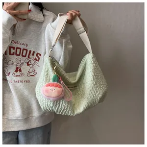 Detail of light green pleated cloud bag with pink peach plush charm and wide strap