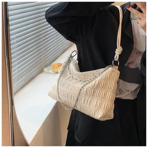 Detail of beige ruched tote bag featuring knotted rope strap and silver chain accent