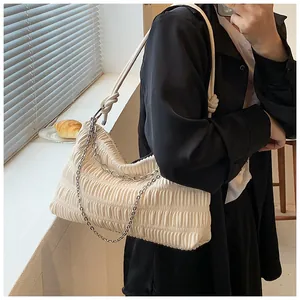Detail of cream pleated tote bag with silver chain and knot strap in a bright window setting