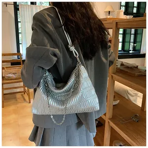 Close-up of pleated silver metallic shoulder bag with silver chain detail on model