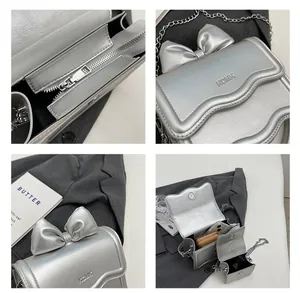 Detailweergave van zilveren mini handtas met strik, ketting en interne opbergruimte