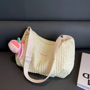 Creamy yellow pleated cloud shoulder bag with peach charm and wide adjustable strap
