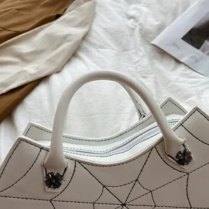 Detail van gotische witte tas met spinnenwebborduursel en kruisvormig metalen beslag