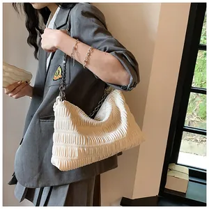 Detail of off-white pleated shoulder bag with silver chain strap and cloud-like texture