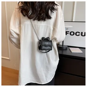 Detailweergave van mini zwarte crossbodytas met zilveren ketting en strikdetail