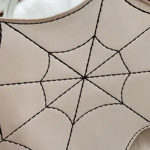 Macro detail van zwart spinnenweb borduursel op beige gothic handtas van leer