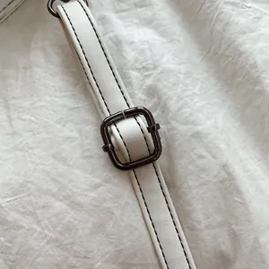 Detail van verstelbare witte PU-lederen riem met zwart stiksel en metalen gesp